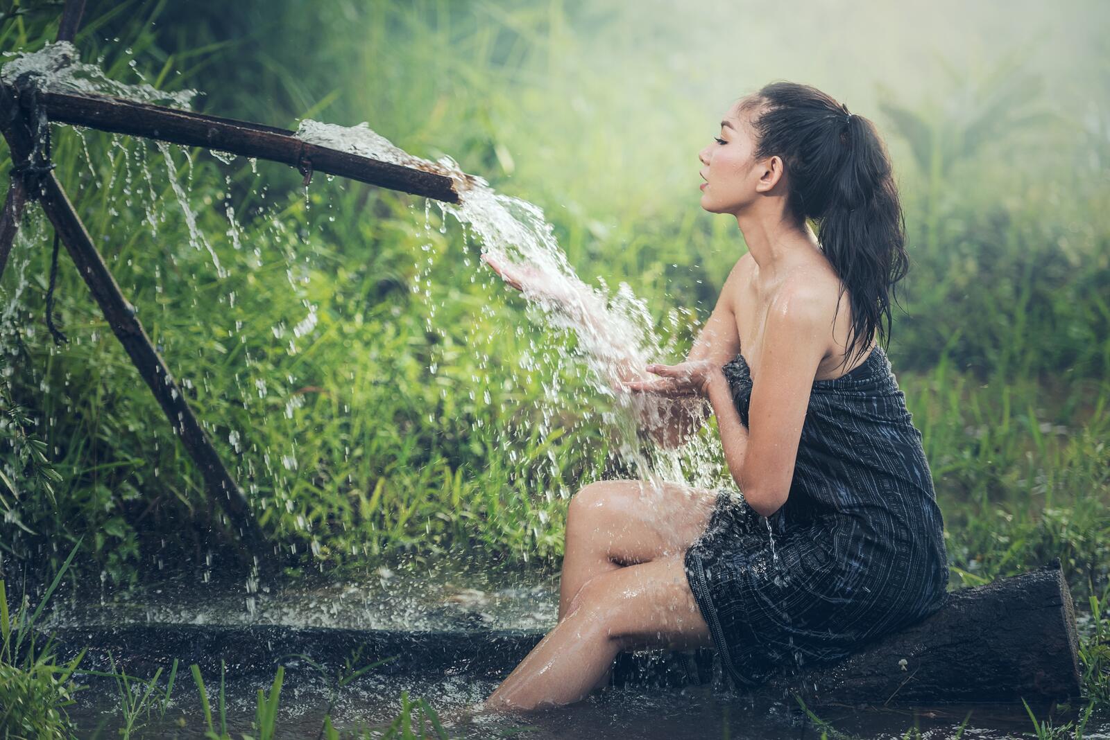Бесплатное фото Темноволосая девушка сидит у самодельного водопада