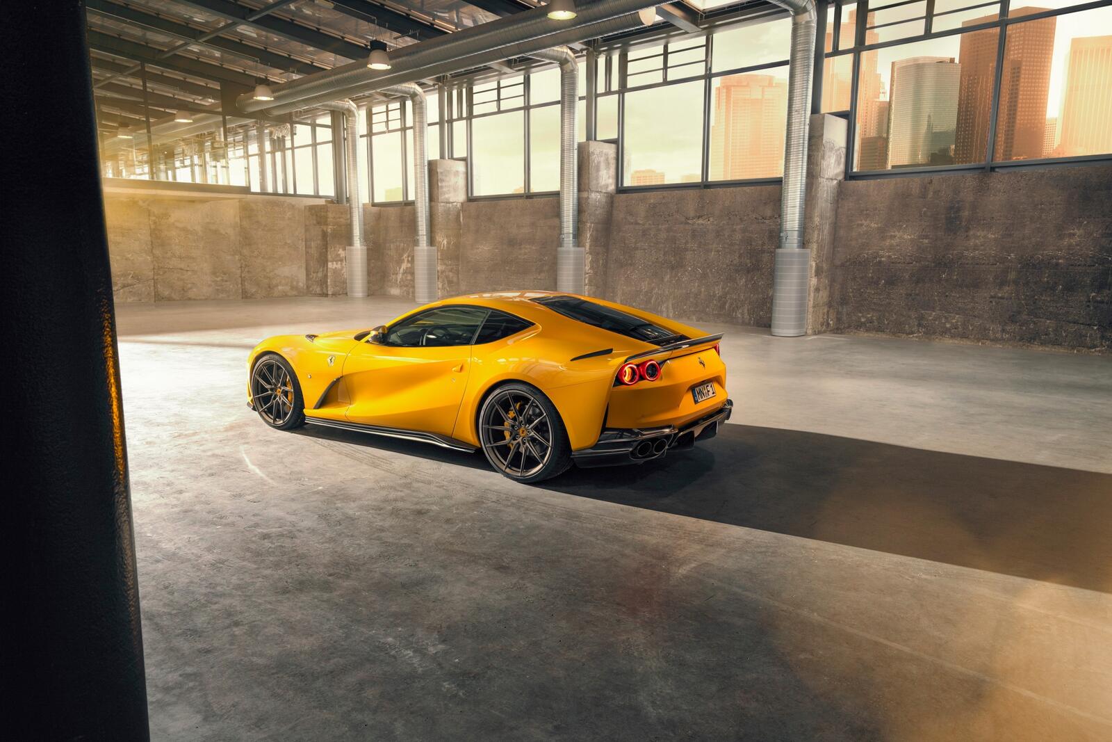 Free photo Yellow ferrari 812 superfast standing in a hangar with large windows