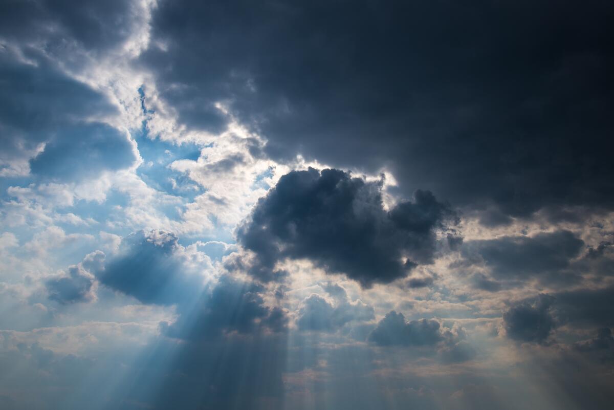 The sun`s rays break through the thick puffy clouds