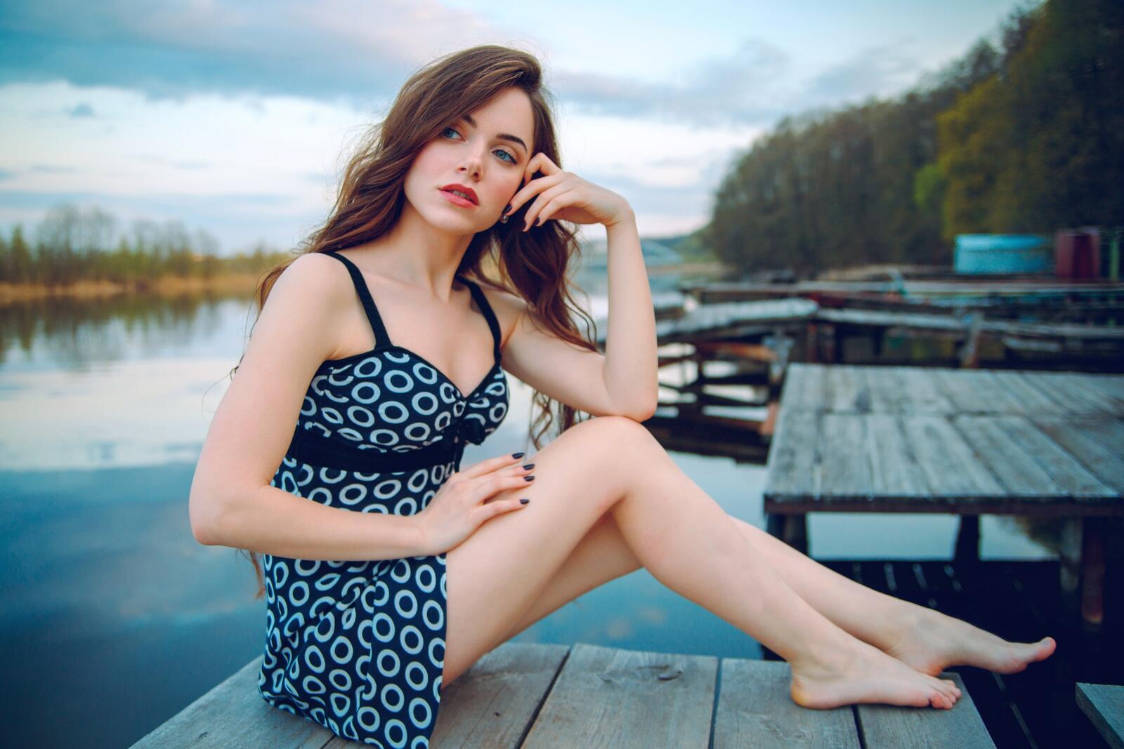 Free photo A girl in an evening dress sits on a wooden bridge