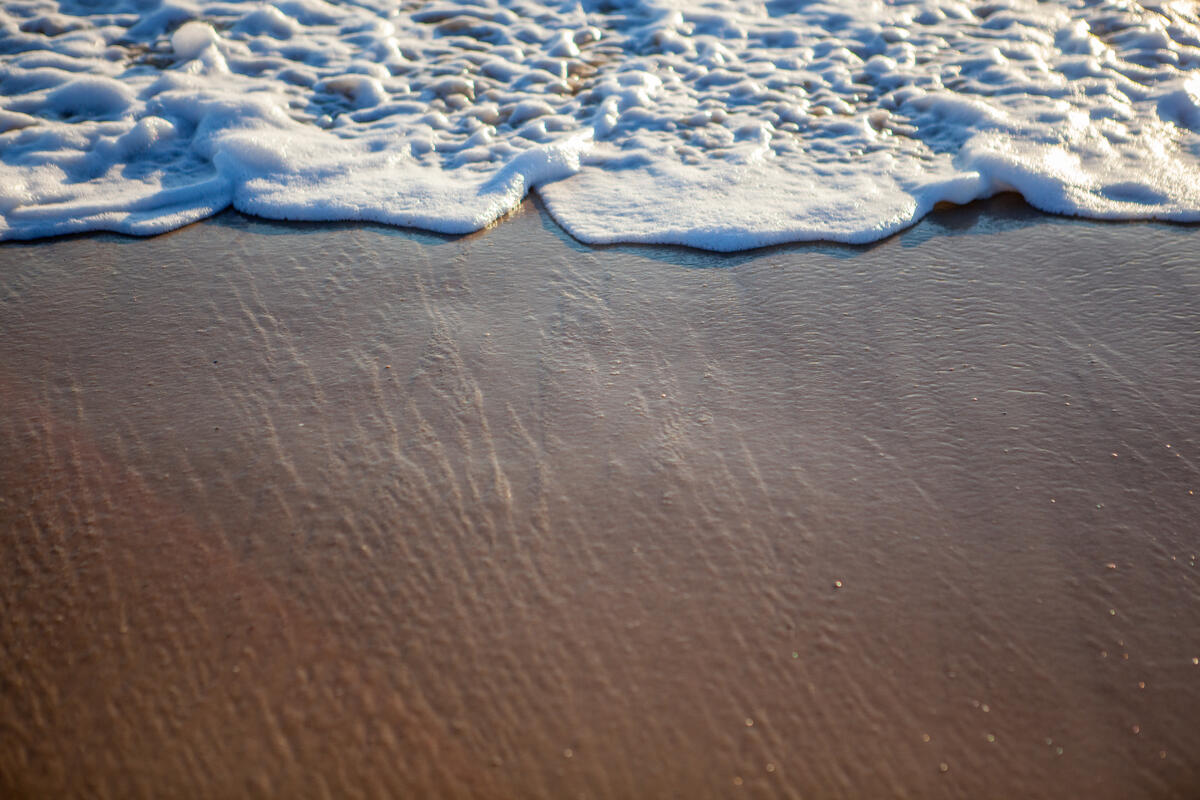Отходящая волна с песочного пляжа