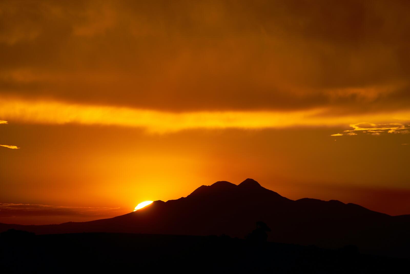 Бесплатное фото Солнце заходящее за склон горы