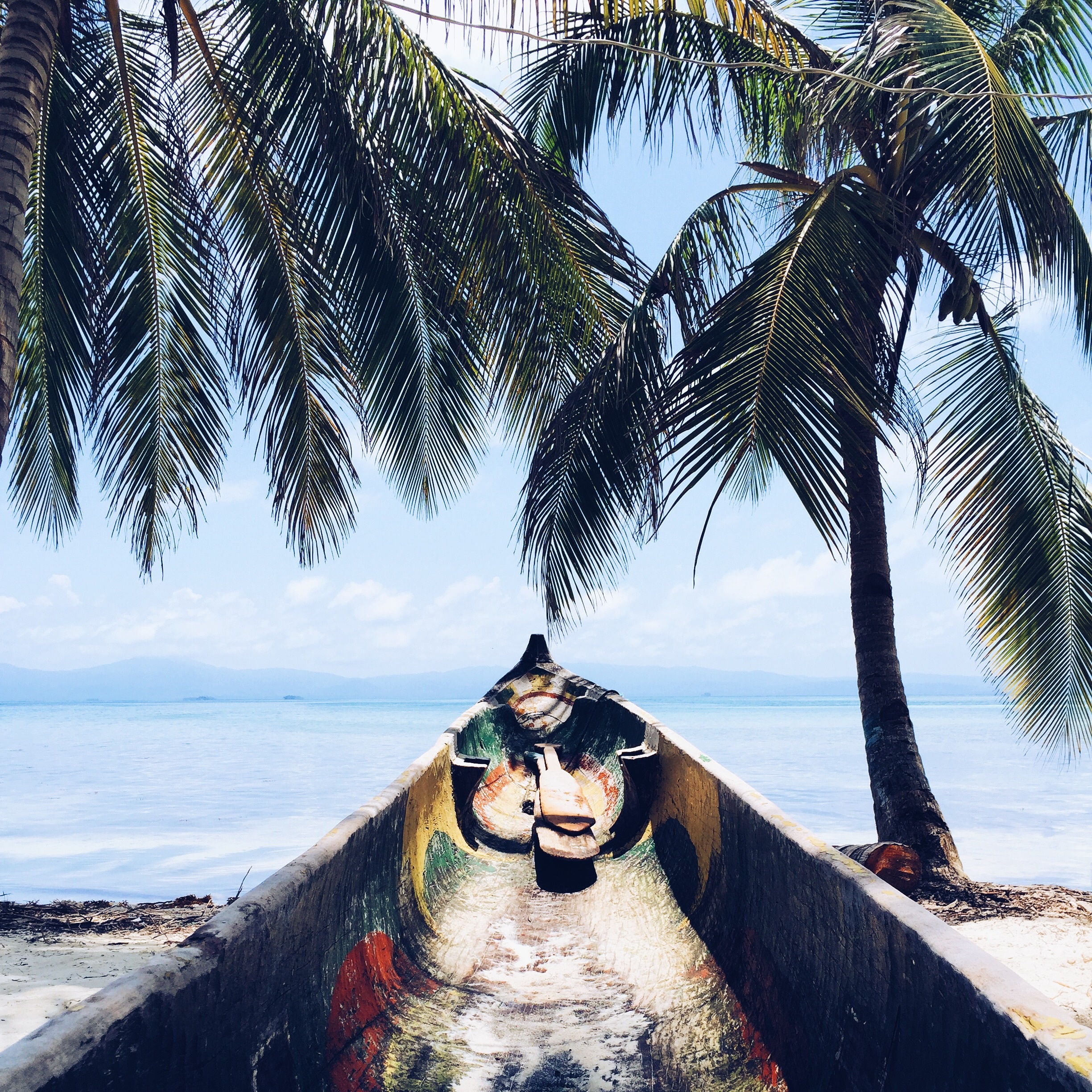 Free photo Canoe on a sandy seashore with palm trees