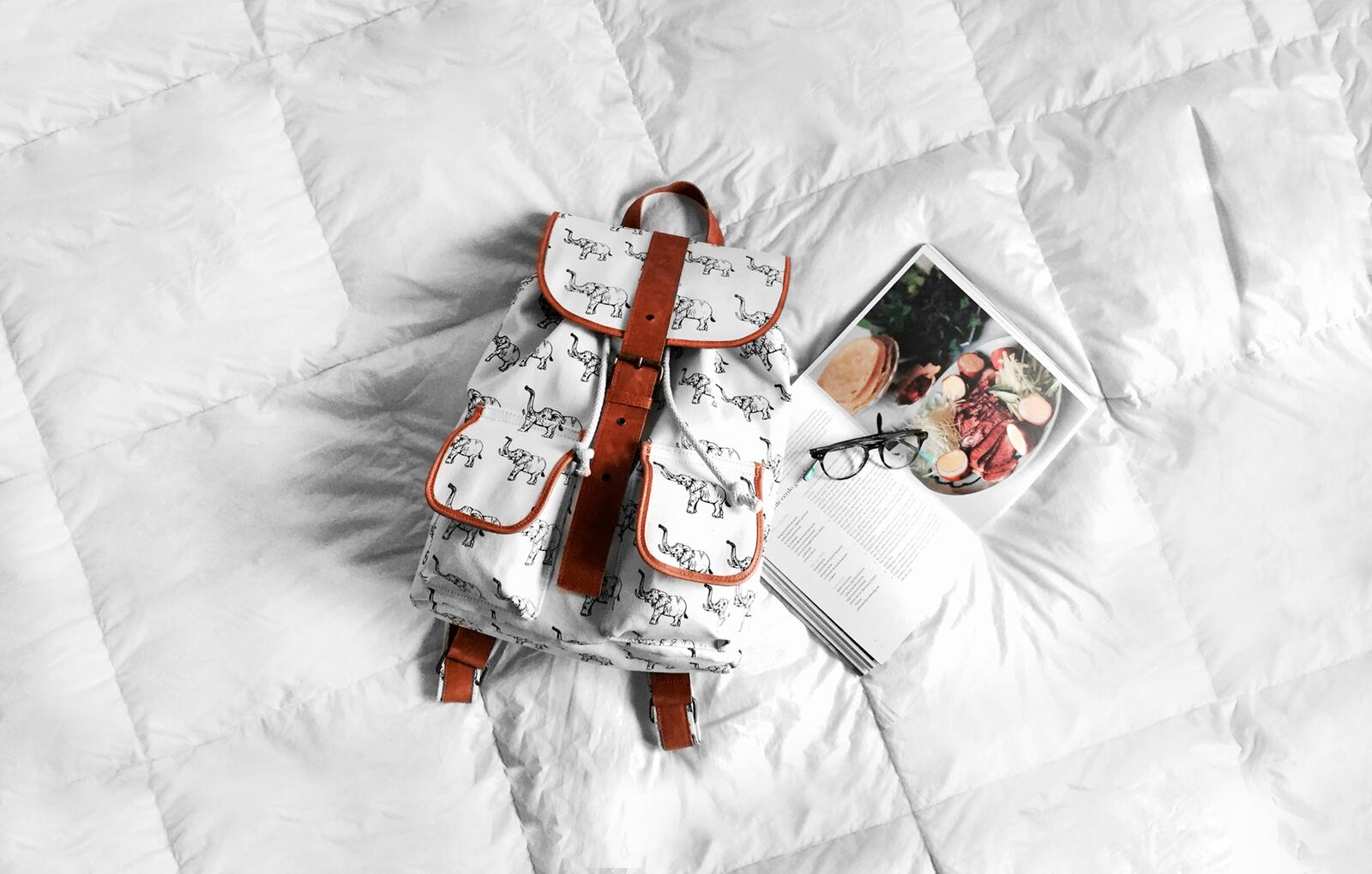 免费照片白色床上躺着一个白色背包