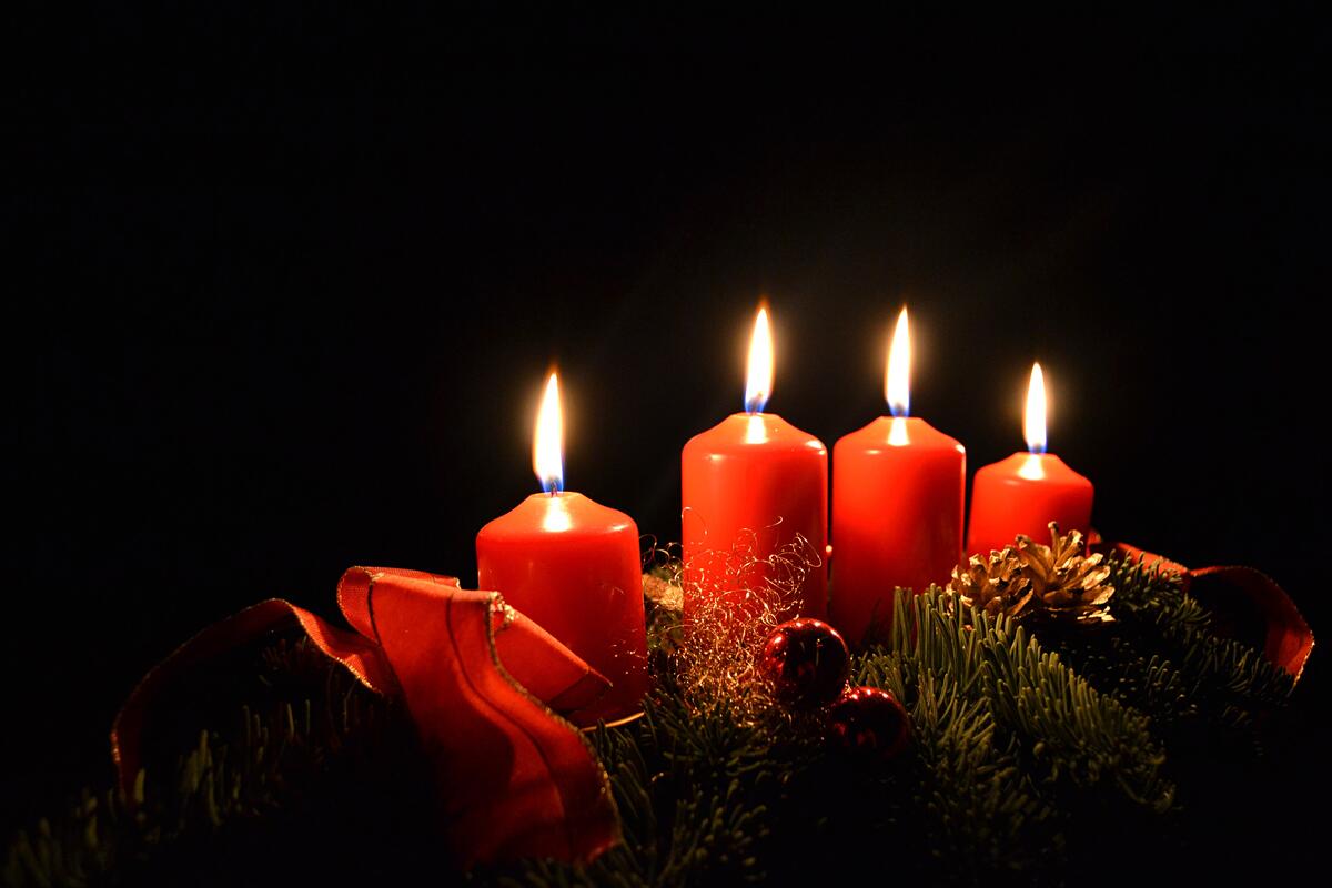 Четыре красные зажженные свечки на черном фоне в рождественскую ночь