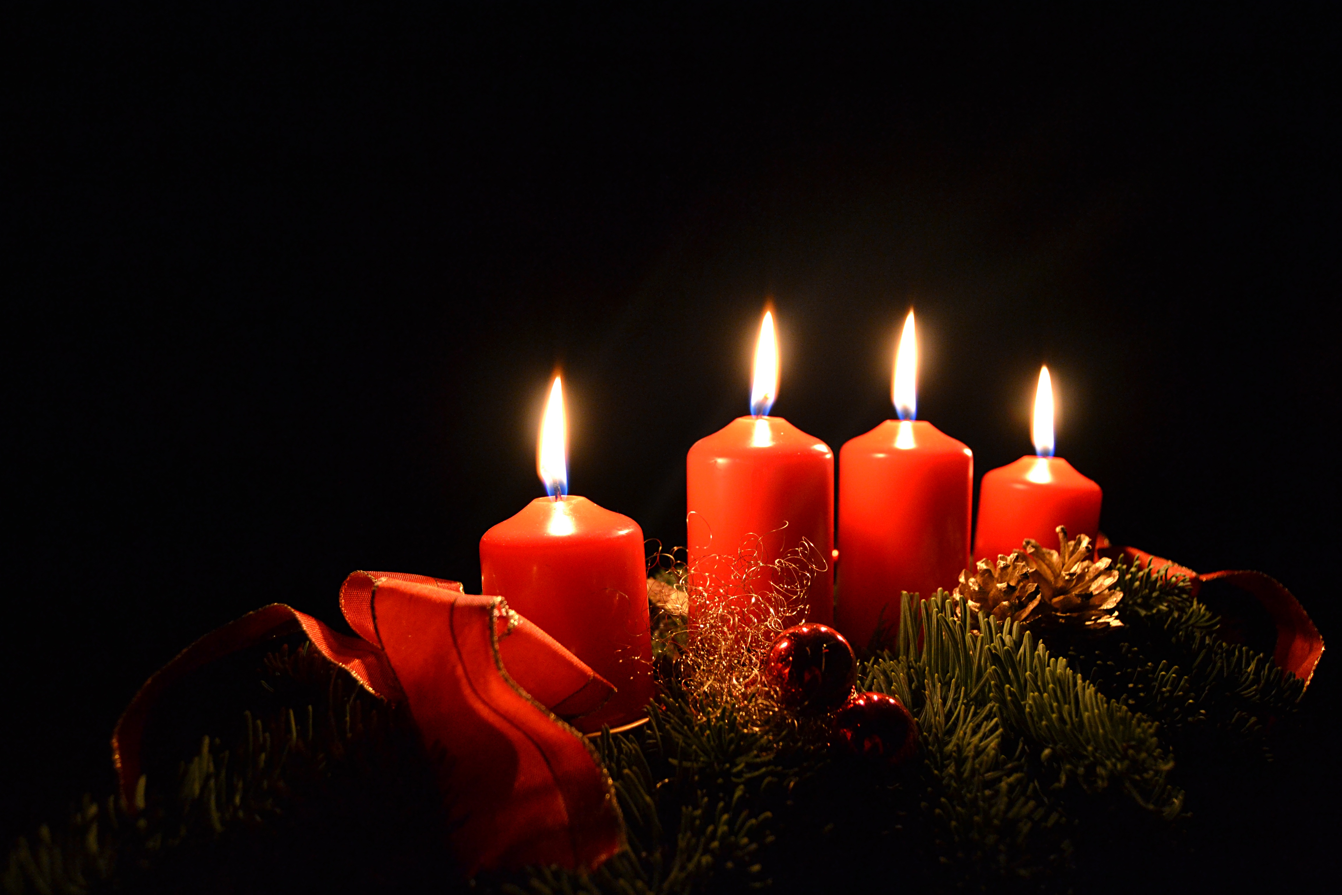 Бесплатное фото Четыре красные зажженные свечки на черном фоне в рождественскую ночь
