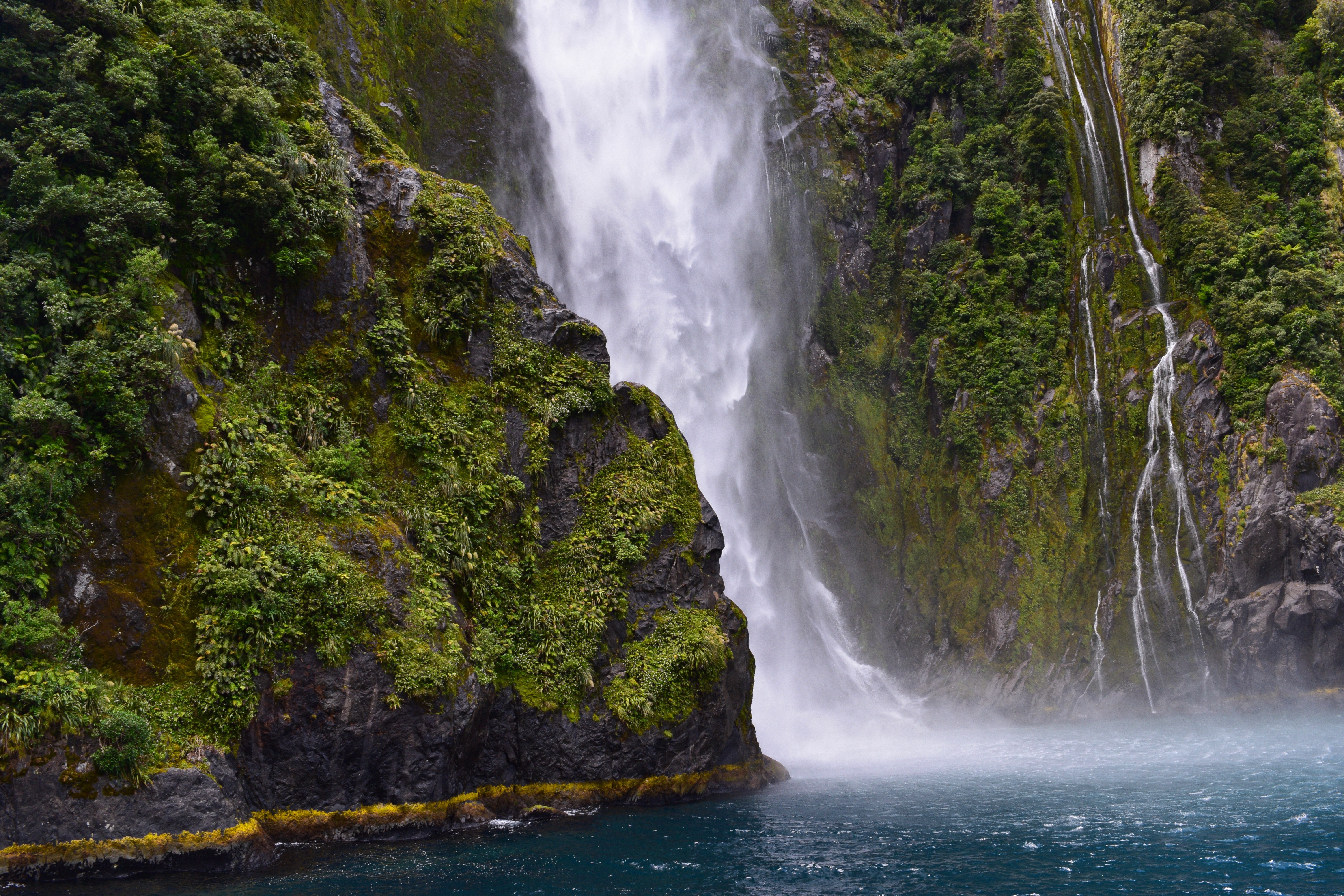 免费照片从长满绿色苔藓的岩石上流下的瀑布