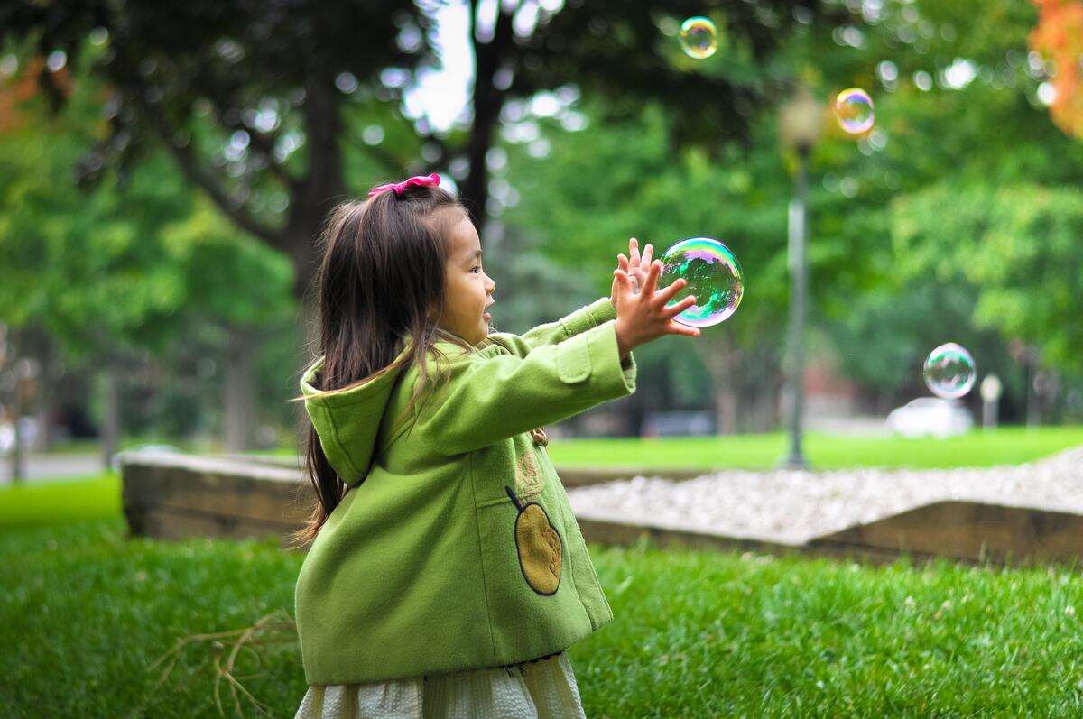 Маленькая девочка играет с мыльными пузырями