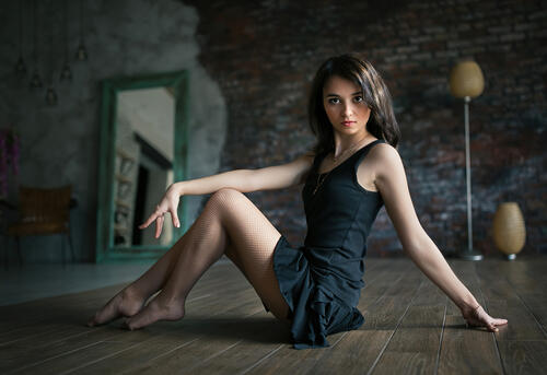 Красивая брюнетка в чермном платье сидит на полу
