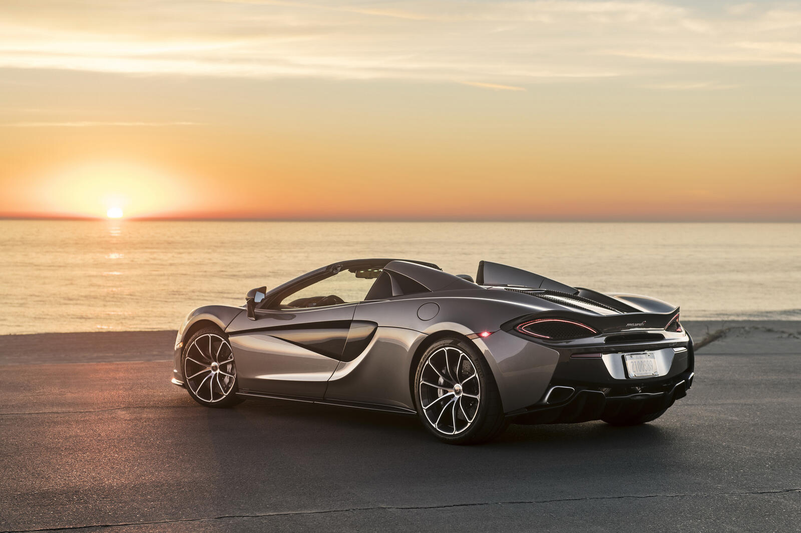 Free photo The Mclaren 570S Spider convertible on the beach at sunset