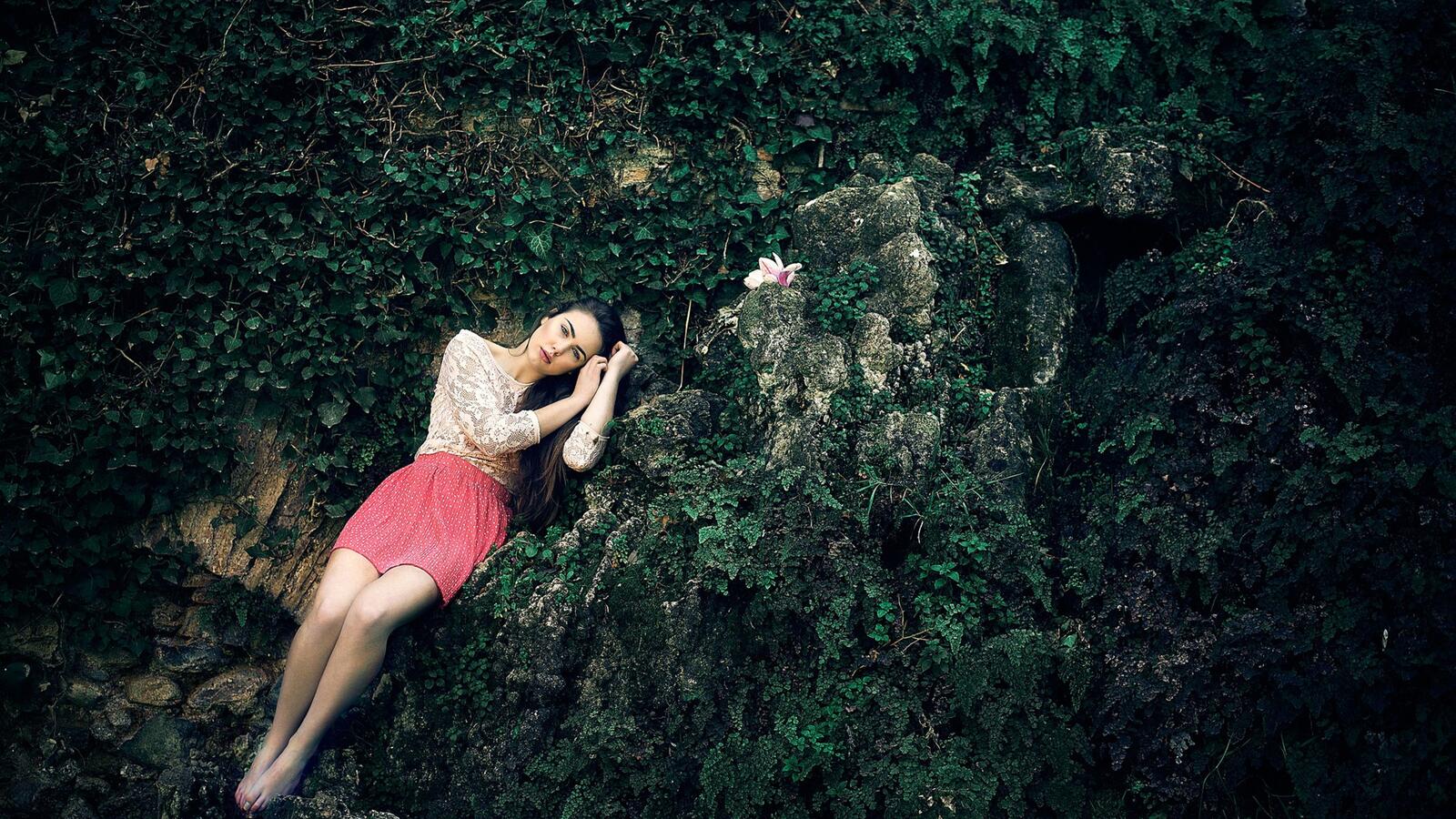 Бесплатное фото Девушка лежит на зеленой растительности