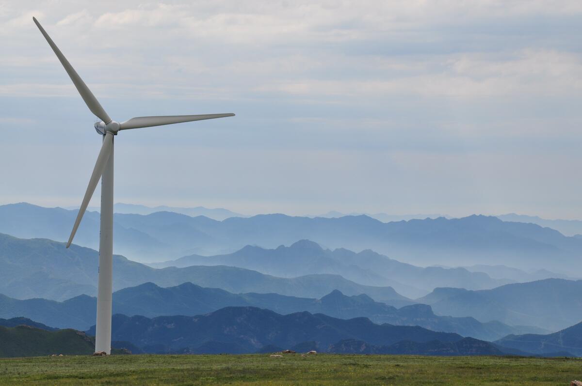 A wind farm against a backdrop of misty mountains
