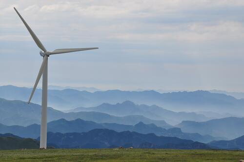 A wind farm against a backdrop of misty mountains