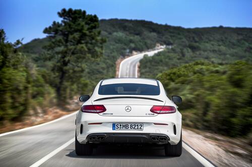 Белый Mercedes AMG C63 S Coupe едет по загородной трассе