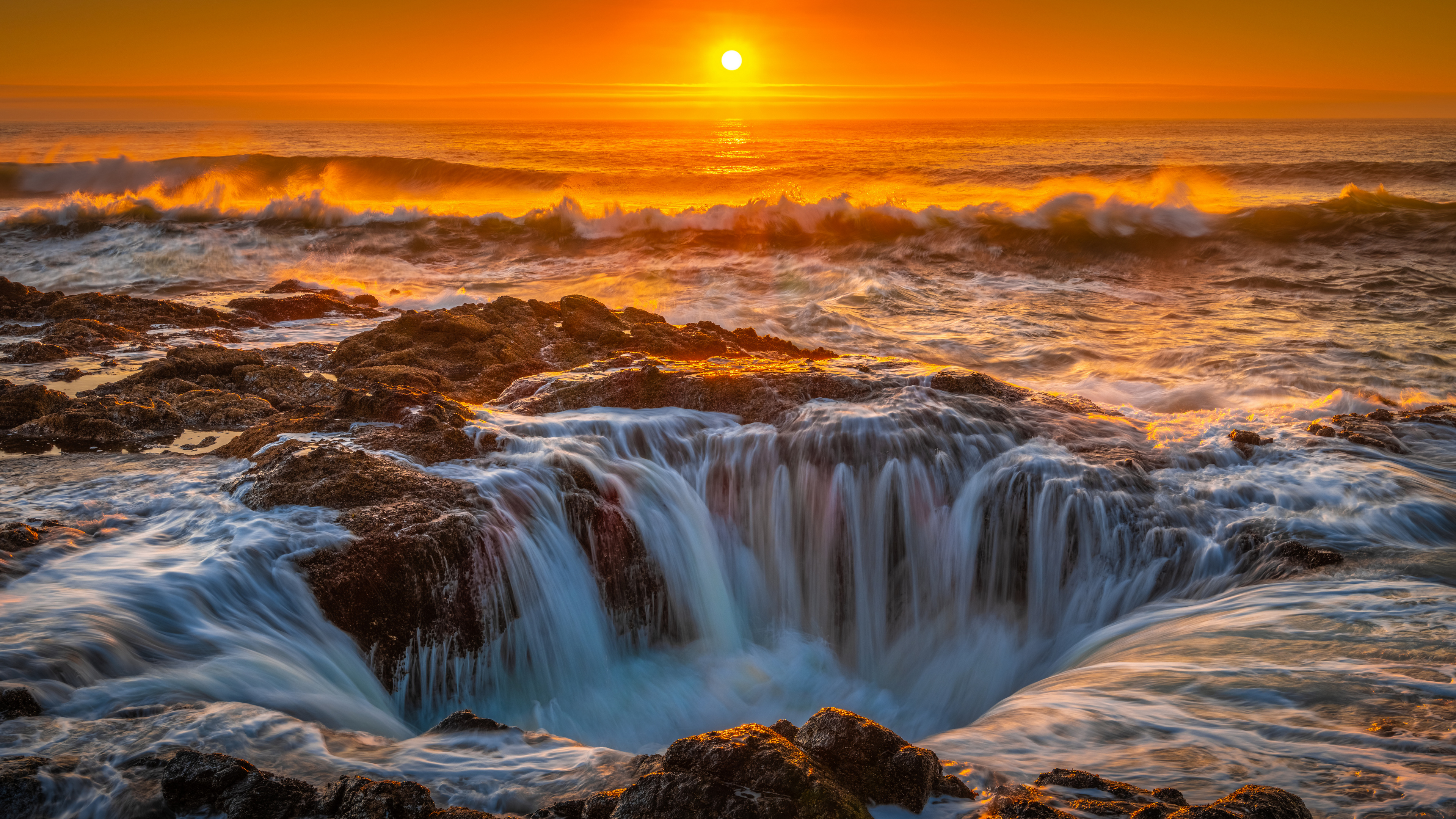 日落时分海中央的瀑布