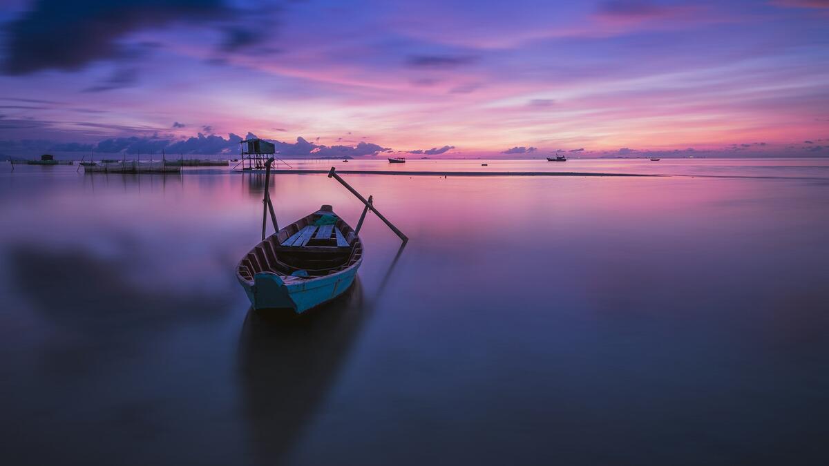 A parked wooden boat with oars in front of a beautiful sunset