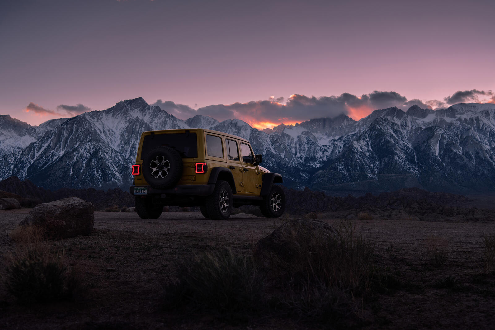 Free photo Jeep Wrangler yellow rear view with snowy mountains in the background