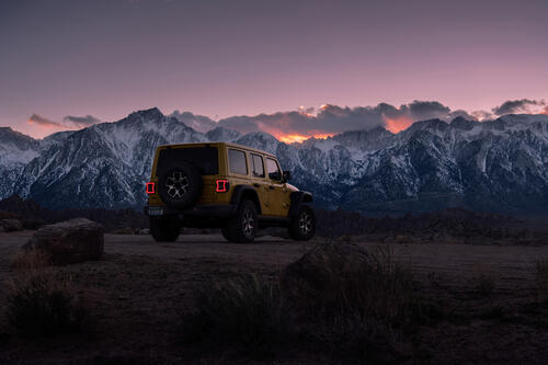 Jeep Wrangler yellow rear view with snowy mountains in the background