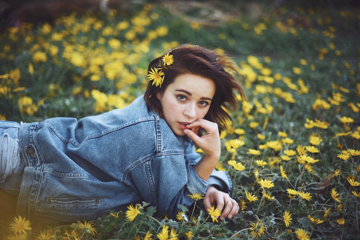 Kaylee Rae with dandelions in her hair lying in a clearing