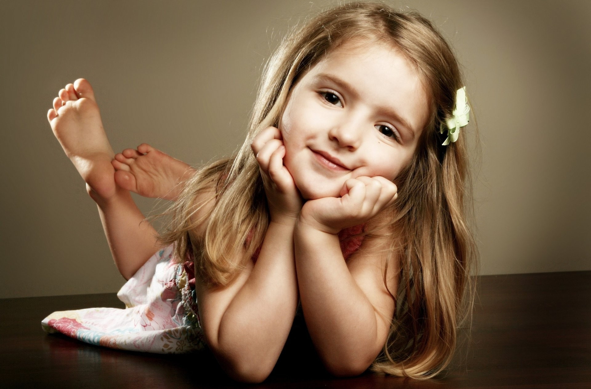 A little girl lying on her stomach and looking at the camera